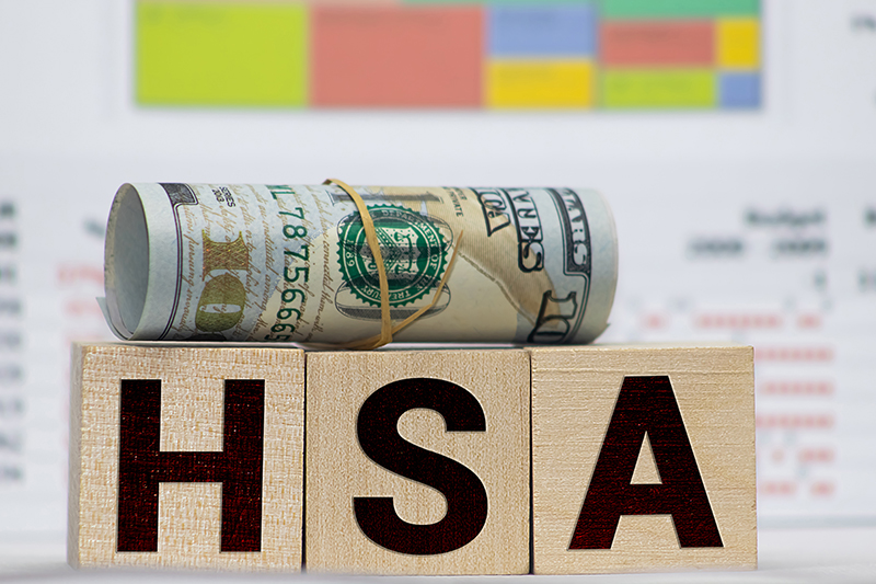Wooden blocks with the word HSA and money bag with stethoscope.