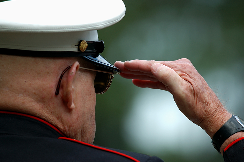 an elderly retired marine salutes during a dedication ceremony