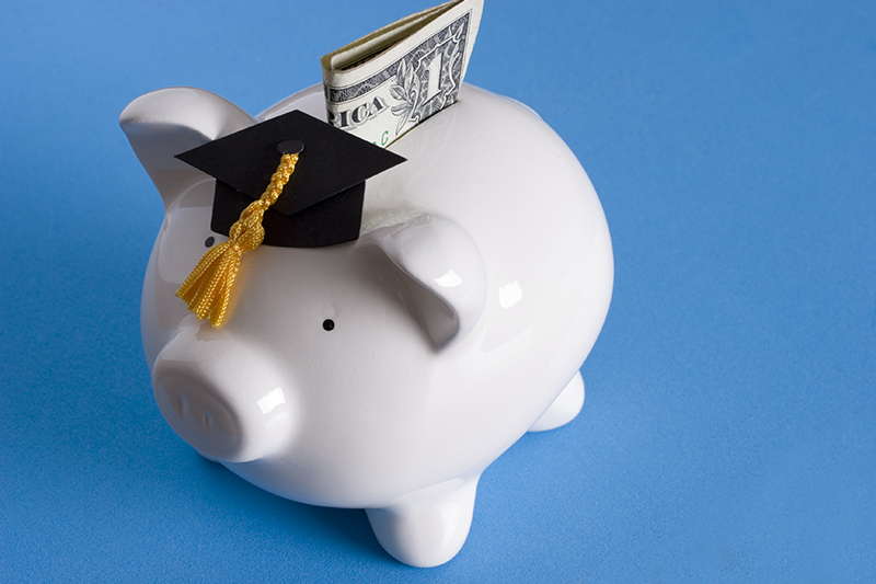 piggy bank with a graduation cap with dollar bill